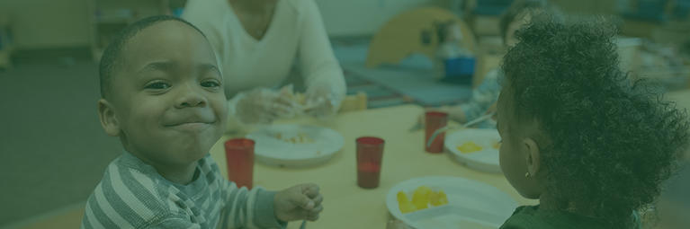 children eating at a table with one boy smiling toward camera